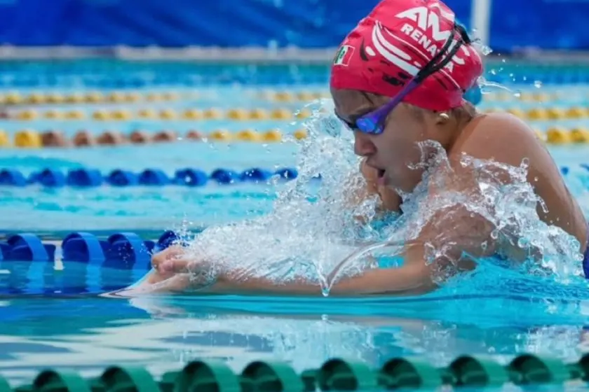 Nadadora del club con gorra roja nadando pecho en una competencia