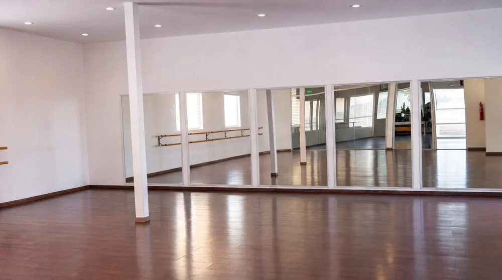 Salón amplio con espejos, barra de ballet y piso de madera